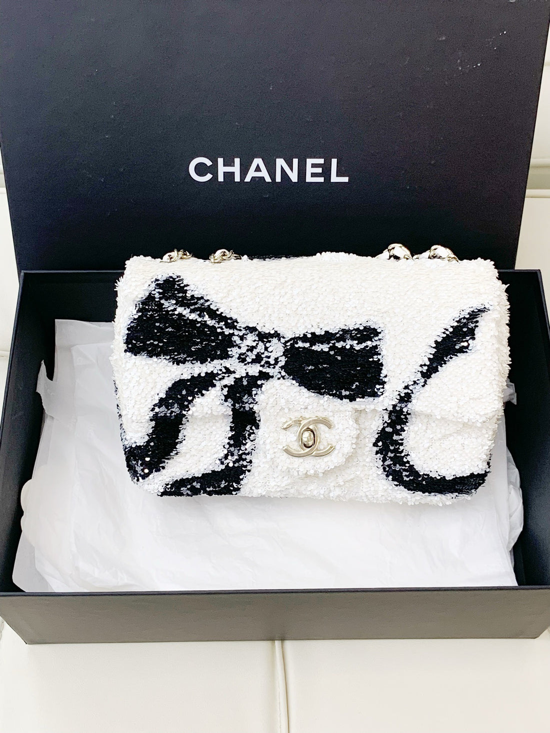 Chanel 25K Collection: Black with a bow, white sequins, and light gold hardware; chain bag.