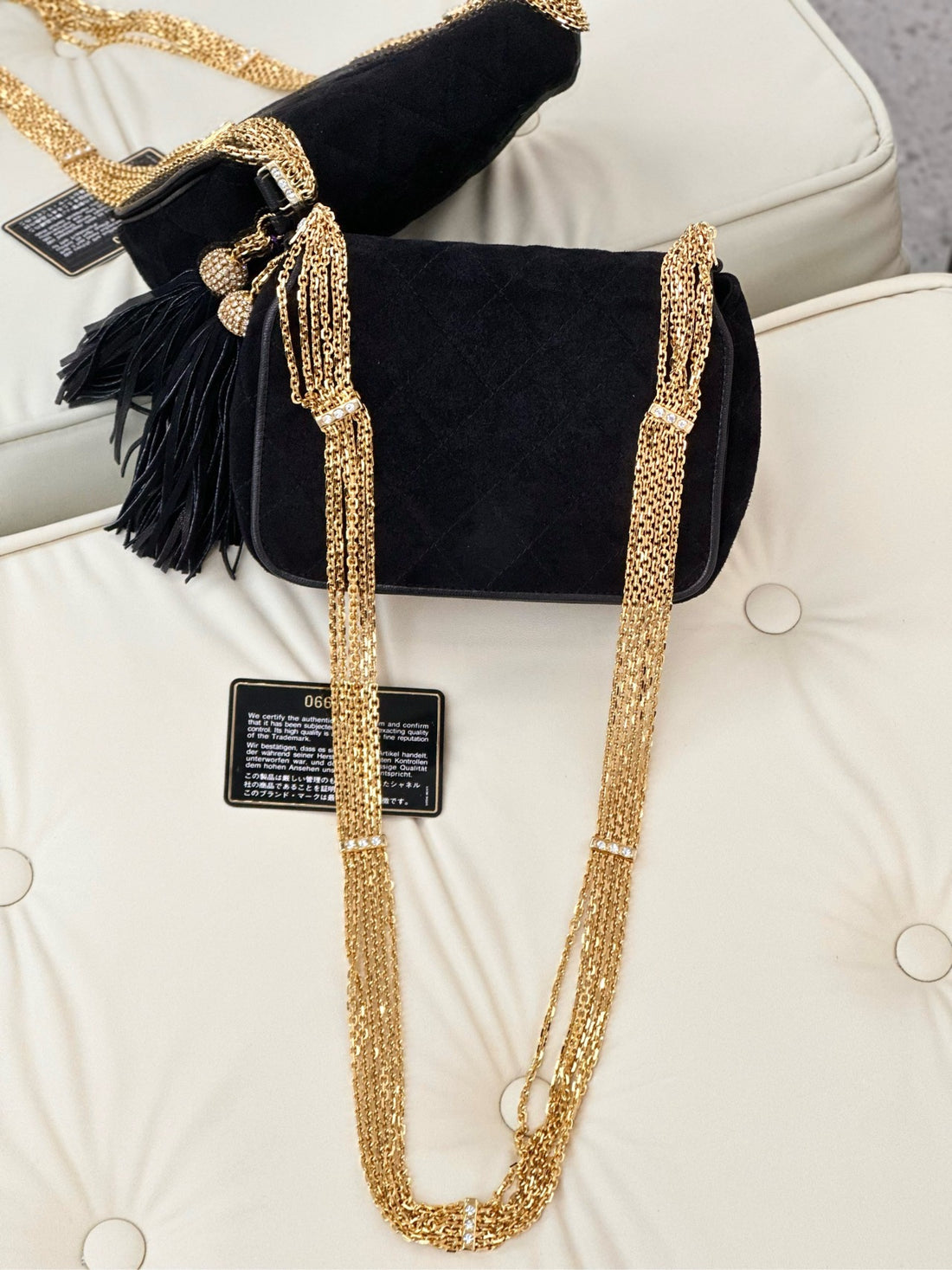 Chanel vintage black suede bag with rhinestone wide shoulder strap, chain, gold buckle, and tassels.